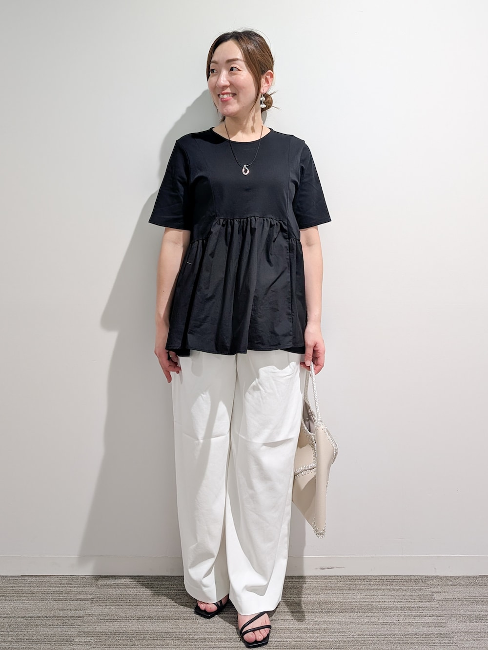 ブラック系のTシャツ/カットソー、ホワイト系のその他パンツ、ホワイト系のハンドバッグを着用したレディースの夏コーディネートの2枚目の写真