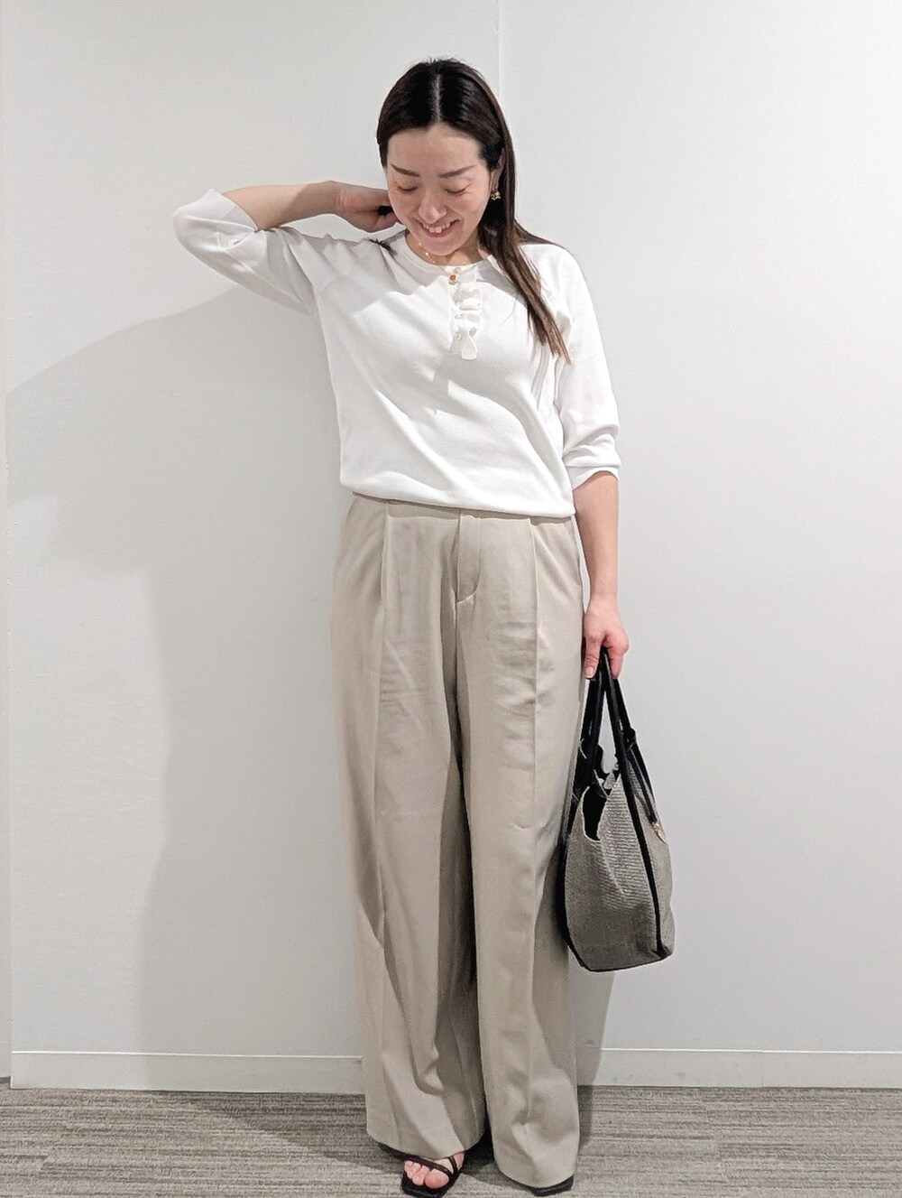 ホワイト系のニット/セーター、ベージュ系のその他パンツ、グレー系のトートバッグを着用したレディースの春コーディネートの2枚目の写真