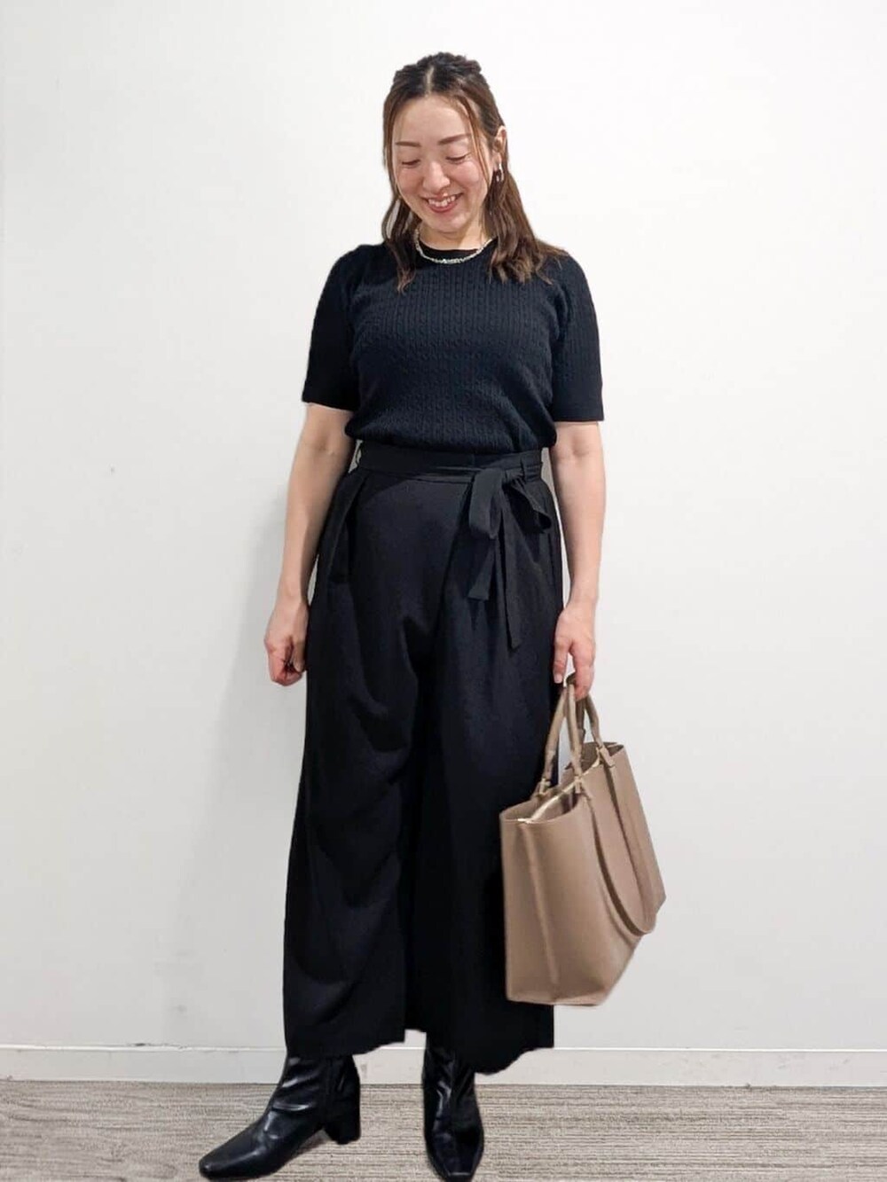 ブラック系のニット/セーター、ブラック系のその他パンツ、ベージュ系のトートバッグを着用したレディースの秋コーディネートの5枚目の写真