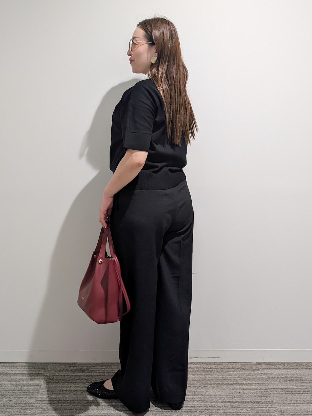ブラック系のニット/セーター、ブラック系のその他パンツ、レッド系のショルダーバッグを着用したレディースの秋コーディネートの4枚目の写真