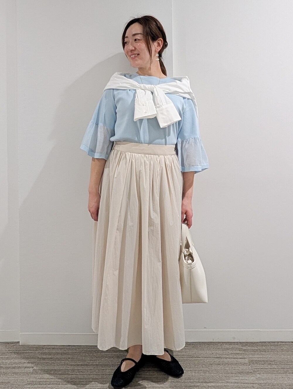 ブルー系のニット/セーター、ベージュ系のその他パンツ、ブラック系のショルダーバッグを着用したレディースの春コーディネートの8枚目の写真