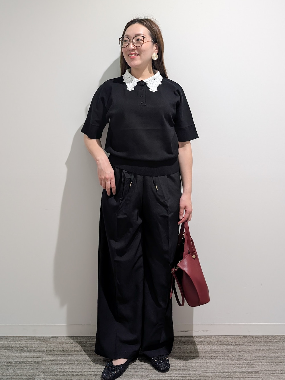 ブラック系のニット/セーター、ブラック系のその他パンツ、レッド系のショルダーバッグを着用したレディースの秋コーディネートの6枚目の写真