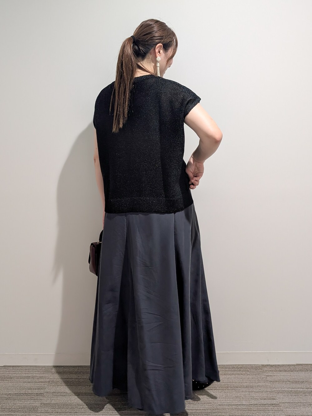 ブラック系のニット/セーター、グレー系のスカート、レッド系のショルダーバッグを着用したレディースの夏コーディネートの6枚目の写真