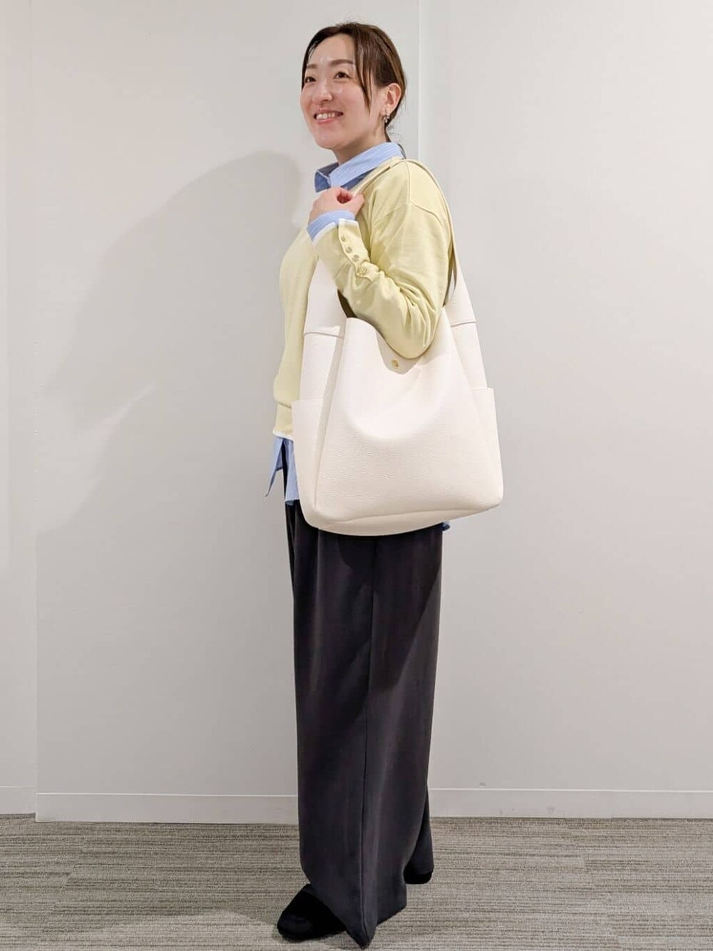 イエロー系のニット/セーター、ブルー系のシャツ/ブラウス、グレー系のその他パンツを着用したレディースの冬コーディネートの4枚目の写真
