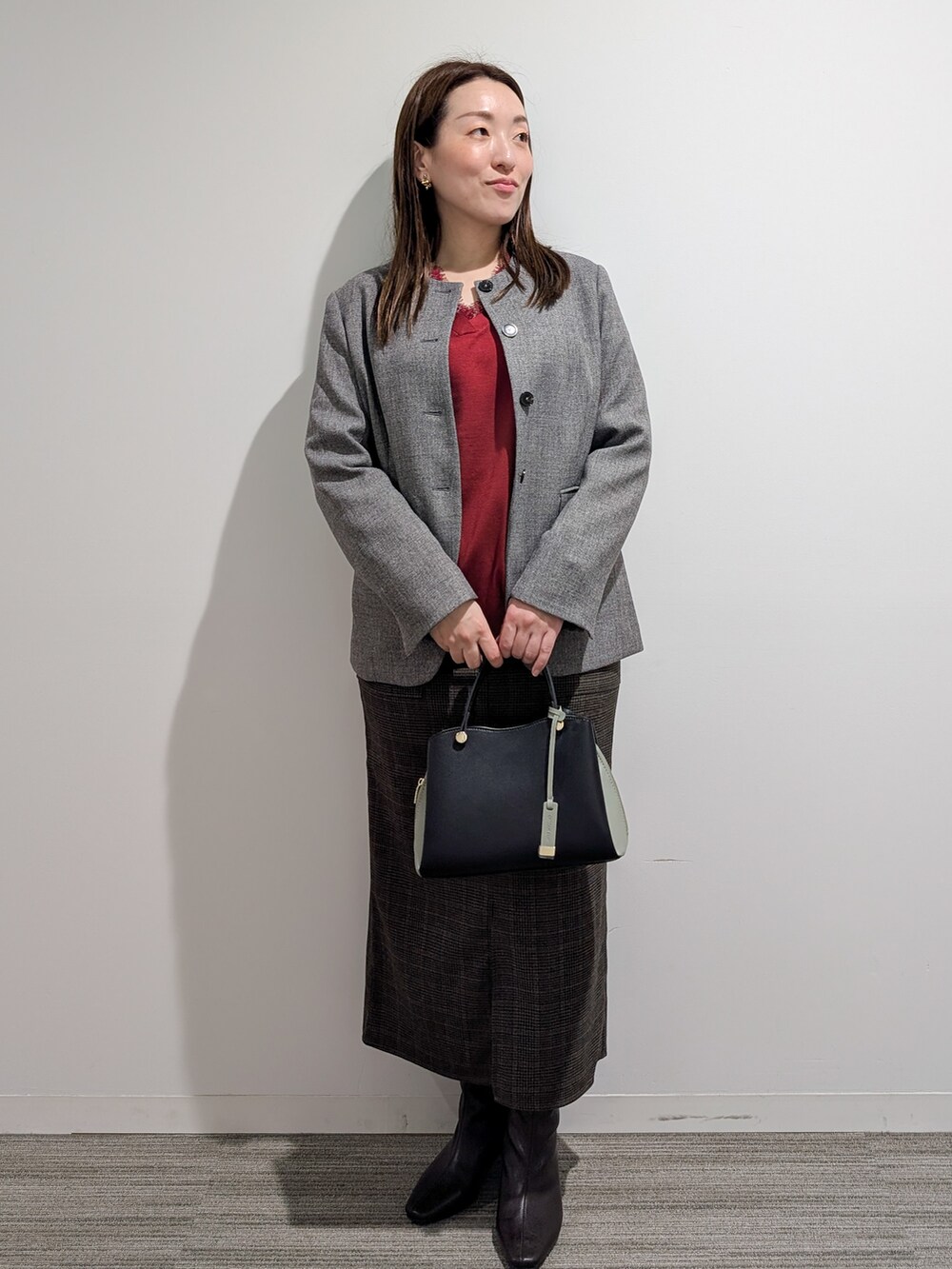 グレー系のノーカラージャケット、レッド系のニット/セーター、ブラウン系のスカートを着用したレディースの秋コーディネートの3枚目の写真
