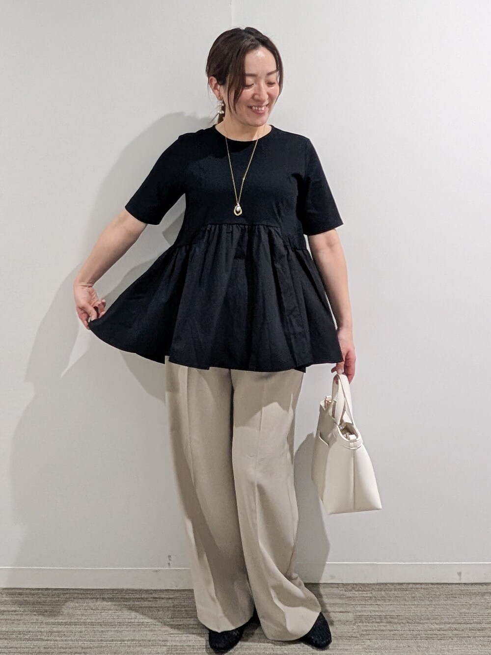 ブラック系のTシャツ/カットソー、ベージュ系のその他パンツ、ホワイト系のショルダーバッグを着用したレディースの春コーディネートの9枚目の写真