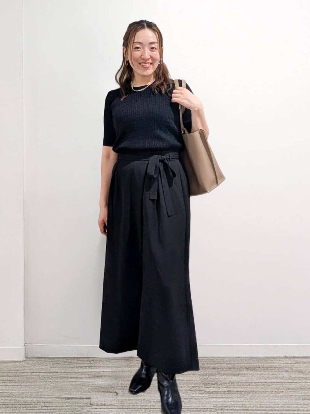ブラック系のニット/セーター、ブラック系のその他パンツ、ベージュ系のトートバッグを着用したレディースの秋コーディネートの4枚目の写真