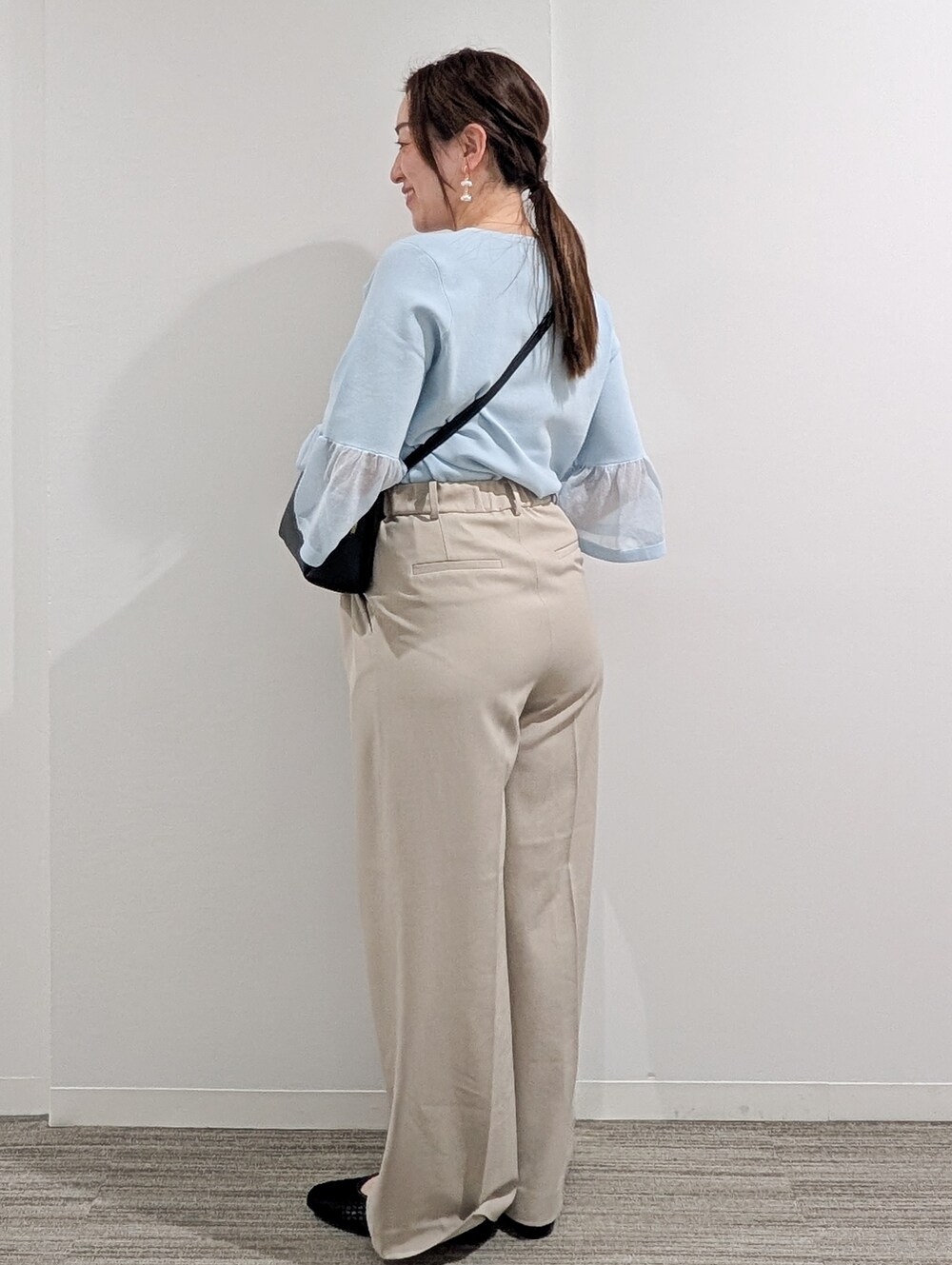ブルー系のニット/セーター、ベージュ系のその他パンツ、ブラック系のショルダーバッグを着用したレディースの春コーディネートの4枚目の写真