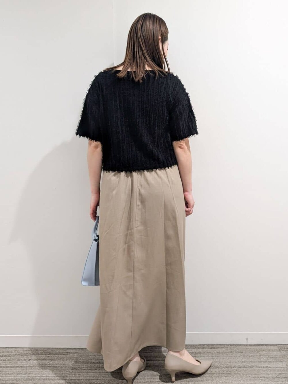 ブラック系のニット/セーター、ベージュ系のワンピース、ブルー系のトートバッグを着用したレディースの夏コーディネートの5枚目の写真