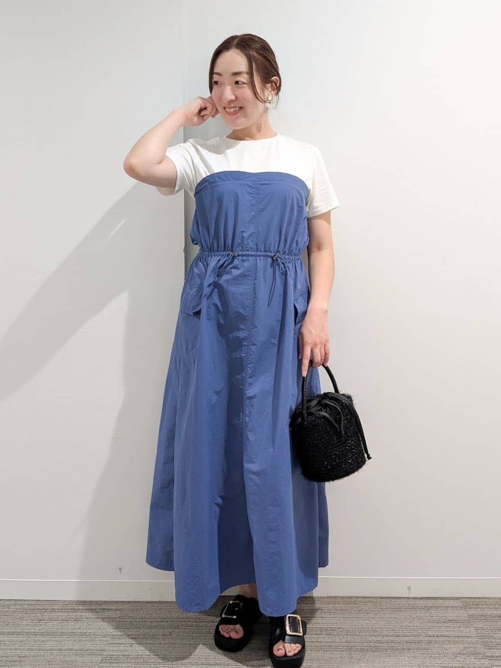 ブルー系のワンピース、ブラック系のハンドバッグ、ブラック系のサンダルを着用したレディースの夏コーディネートの2枚目の写真