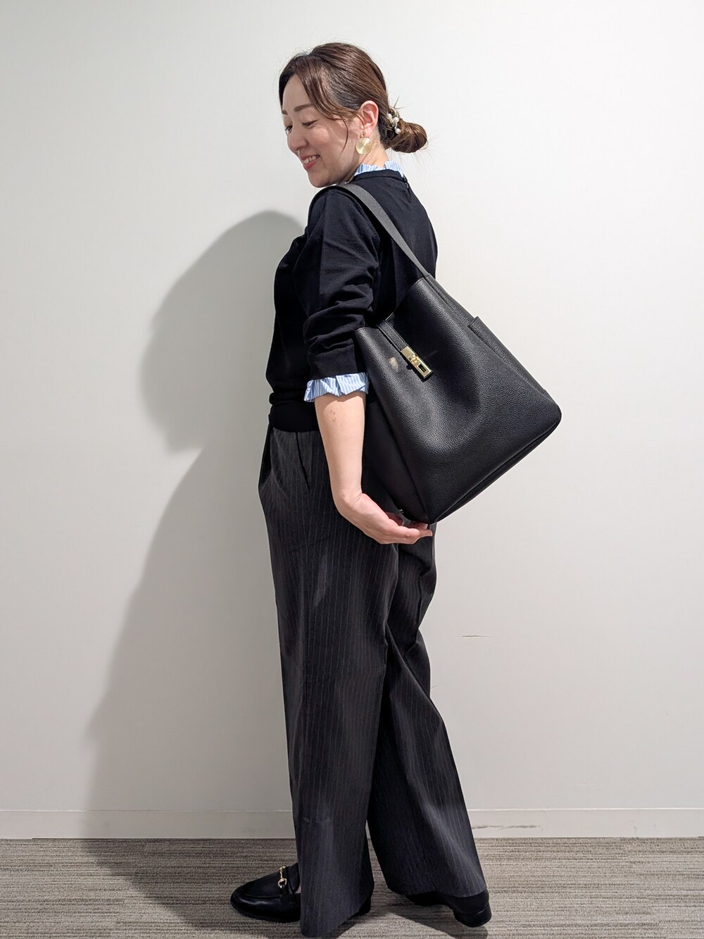 ブラック系のニット/セーター、グレー系のその他パンツ、ブラック系のトートバッグを着用したレディースの秋コーディネートの3枚目の写真