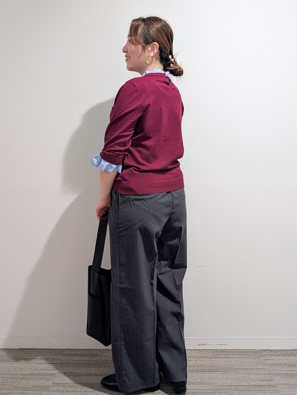 レッド系のニット/セーター、グレー系のその他パンツ、ブラック系のトートバッグを着用したレディースの秋コーディネートの3枚目の写真