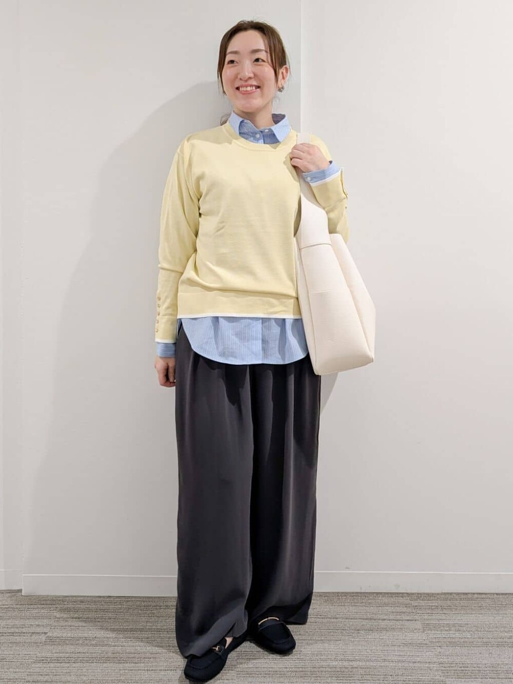 イエロー系のニット/セーター、ブルー系のシャツ/ブラウス、グレー系のその他パンツを着用したレディースの冬コーディネートの2枚目の写真