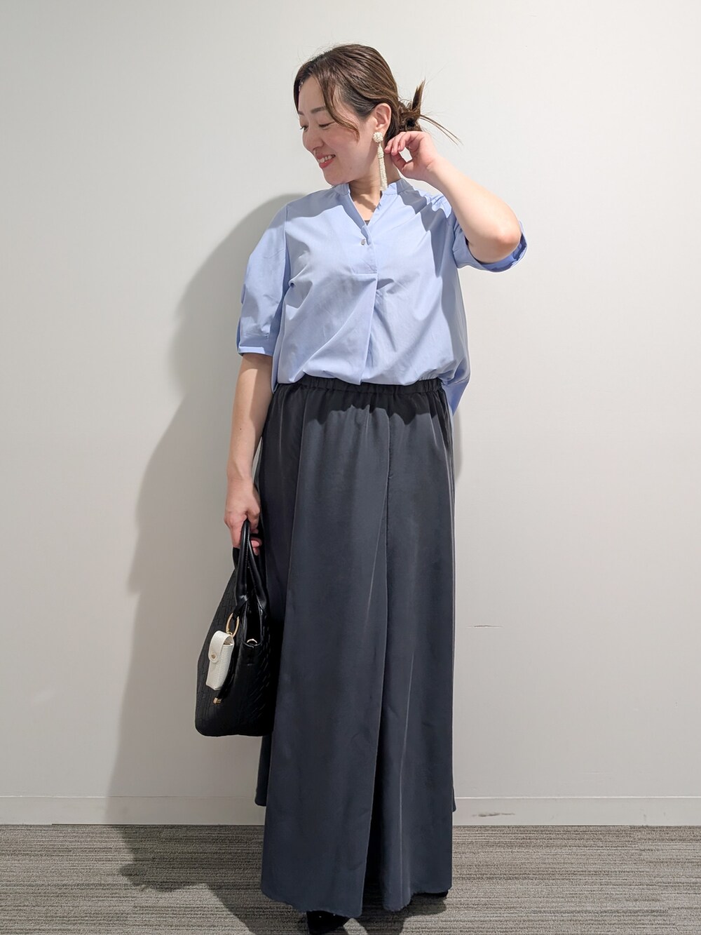 ブルー系のシャツ/ブラウス、グレー系のスカート、ブラック系のトートバッグを着用したレディースの夏コーディネートの4枚目の写真