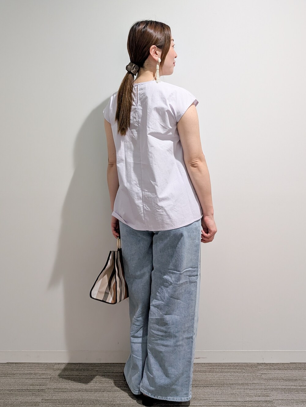 パープル系のシャツ/ブラウス、ブルー系のデニムパンツ、ブラック系のトートバッグを着用したレディースの夏コーディネートの4枚目の写真