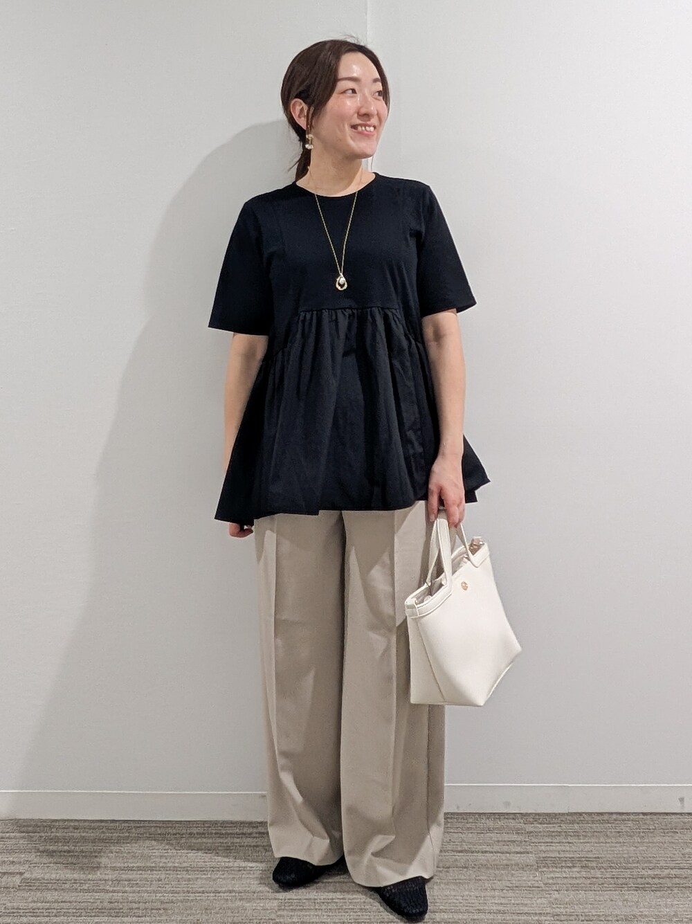ブラック系のTシャツ/カットソー、ベージュ系のその他パンツ、ホワイト系のショルダーバッグを着用したレディースの春コーディネートの3枚目の写真