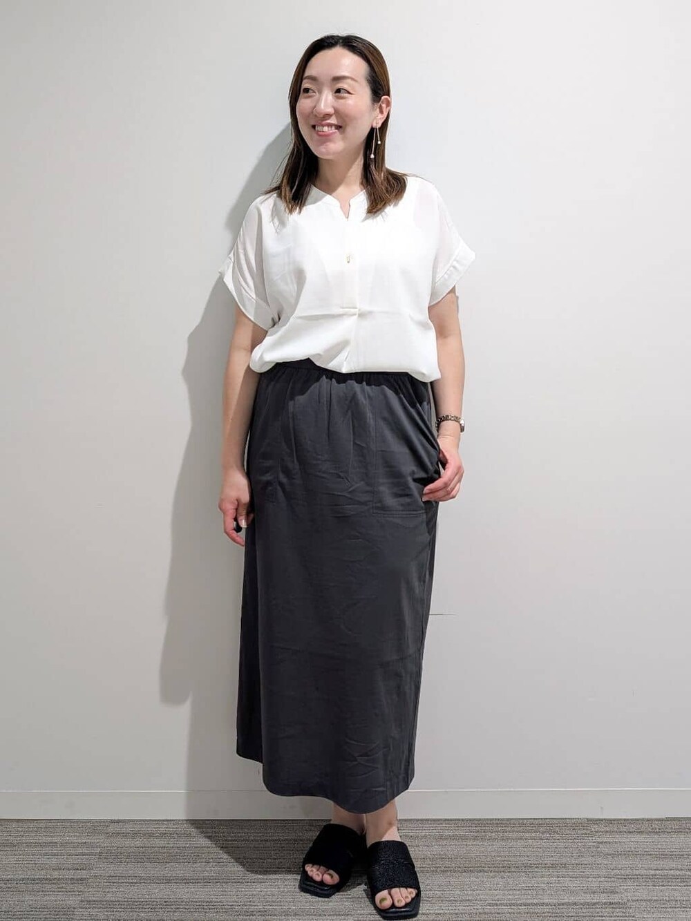 ホワイト系のシャツ/ブラウス、グレー系のスカート、ブラック系のサンダルを着用したレディースの夏コーディネートの3枚目の写真