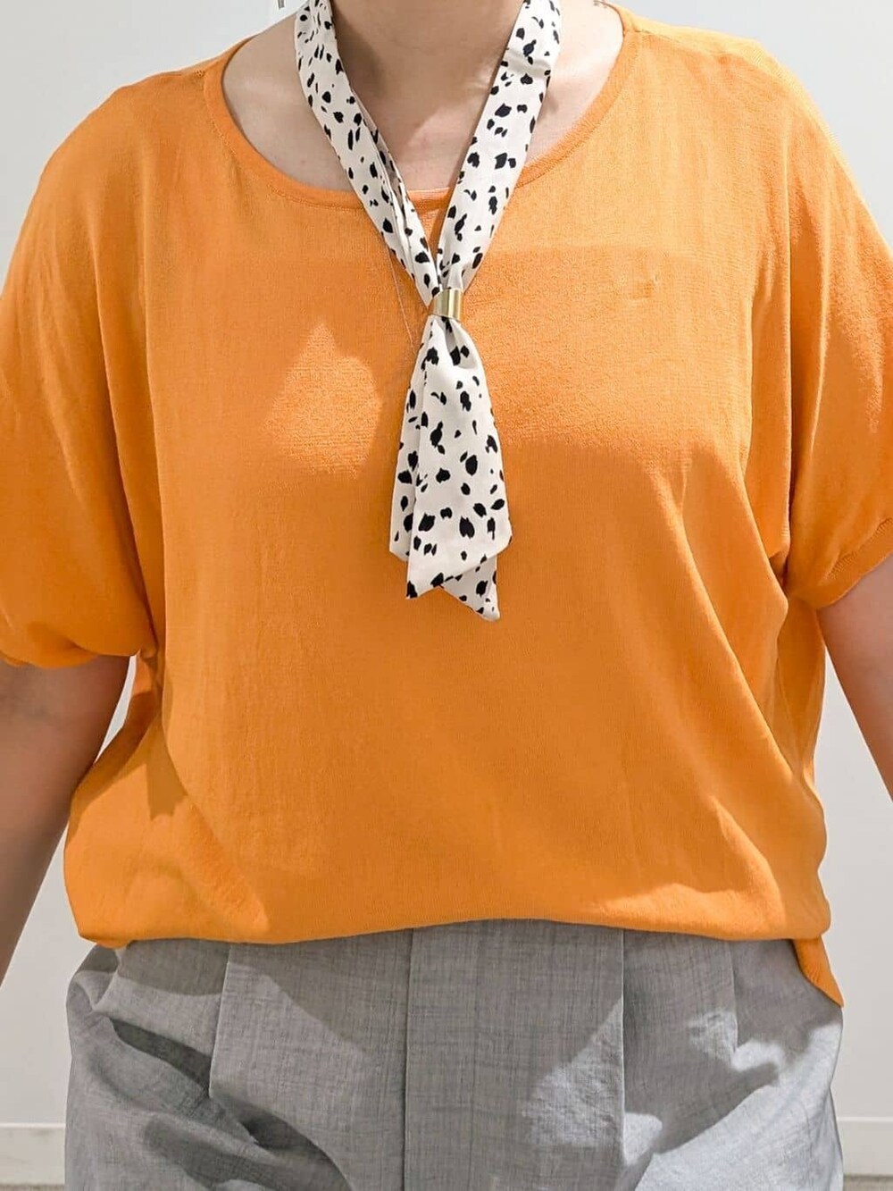 オレンジ系のニット/セーター、グレー系のその他パンツ、ブラック系のサンダルを着用したレディースの夏コーディネートの7枚目の写真