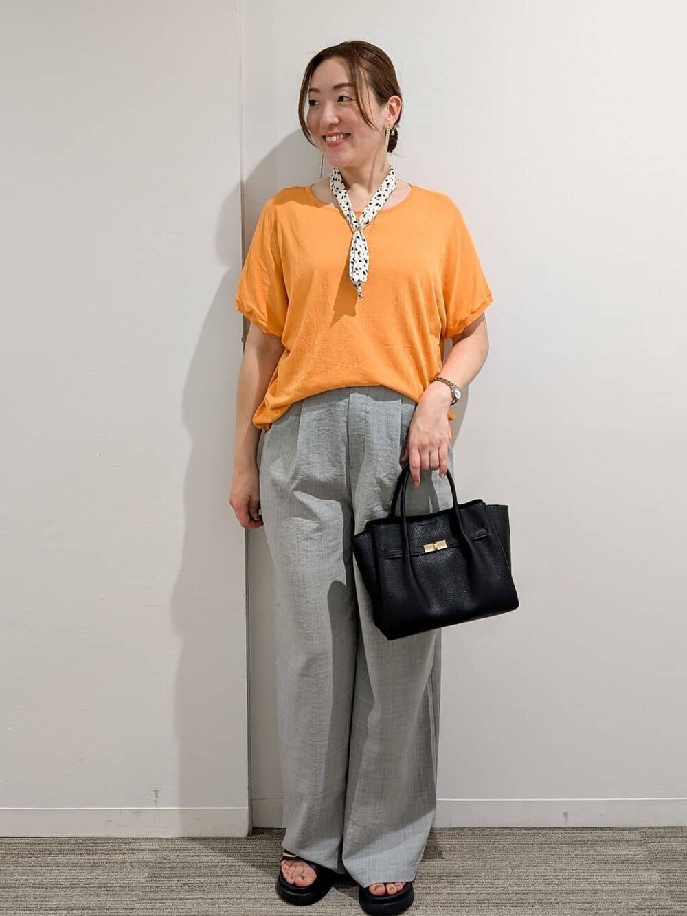 オレンジ系のニット/セーター、グレー系のその他パンツ、ブラック系のサンダルを着用したレディースの夏コーディネートの5枚目の写真