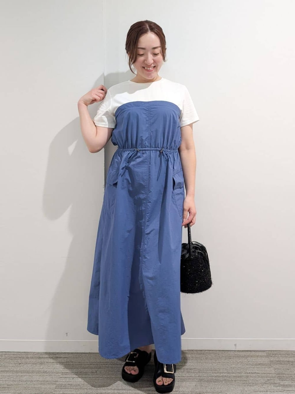ブルー系のワンピース、ブラック系のハンドバッグ、ブラック系のサンダルを着用したレディースの夏コーディネートの3枚目の写真