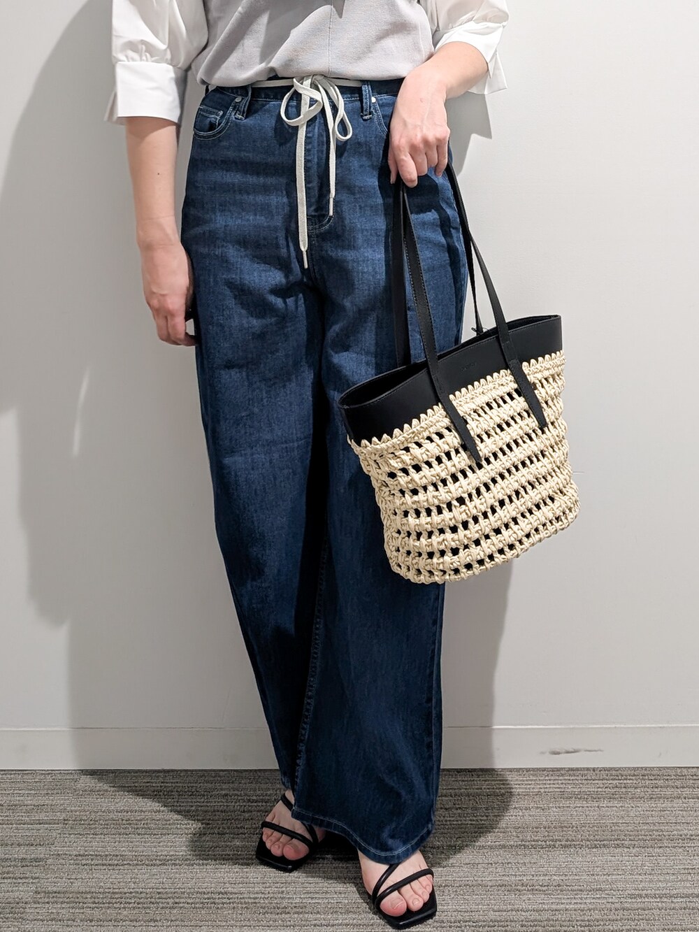 グレー系のニット/セーター、ブルー系のデニムパンツ、ブラック系のトートバッグを着用したレディースの夏コーディネートの6枚目の写真