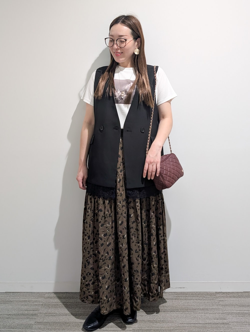 ブラック系のベスト、ホワイト系のTシャツ/カットソー、ブラウン系のスカートを着用したレディースの秋コーディネートの8枚目の写真