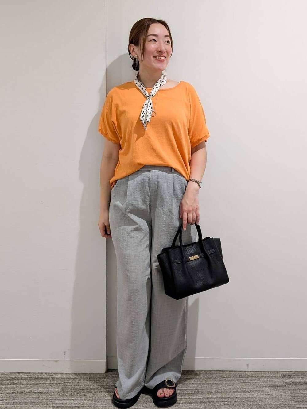 オレンジ系のニット/セーター、グレー系のその他パンツ、ブラック系のサンダルを着用したレディースの夏コーディネートの3枚目の写真