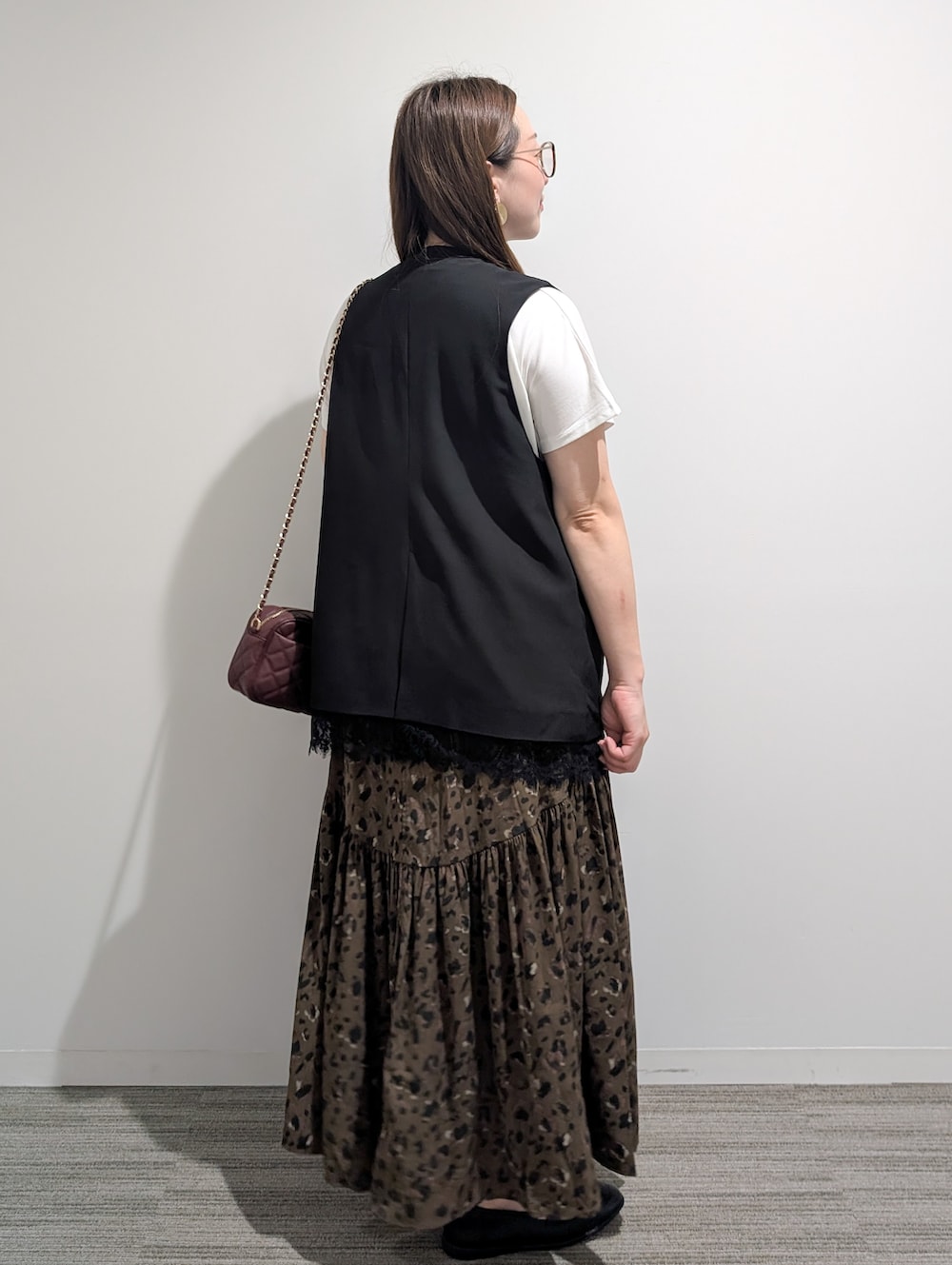 ブラック系のベスト、ホワイト系のTシャツ/カットソー、ブラウン系のスカートを着用したレディースの秋コーディネートの4枚目の写真