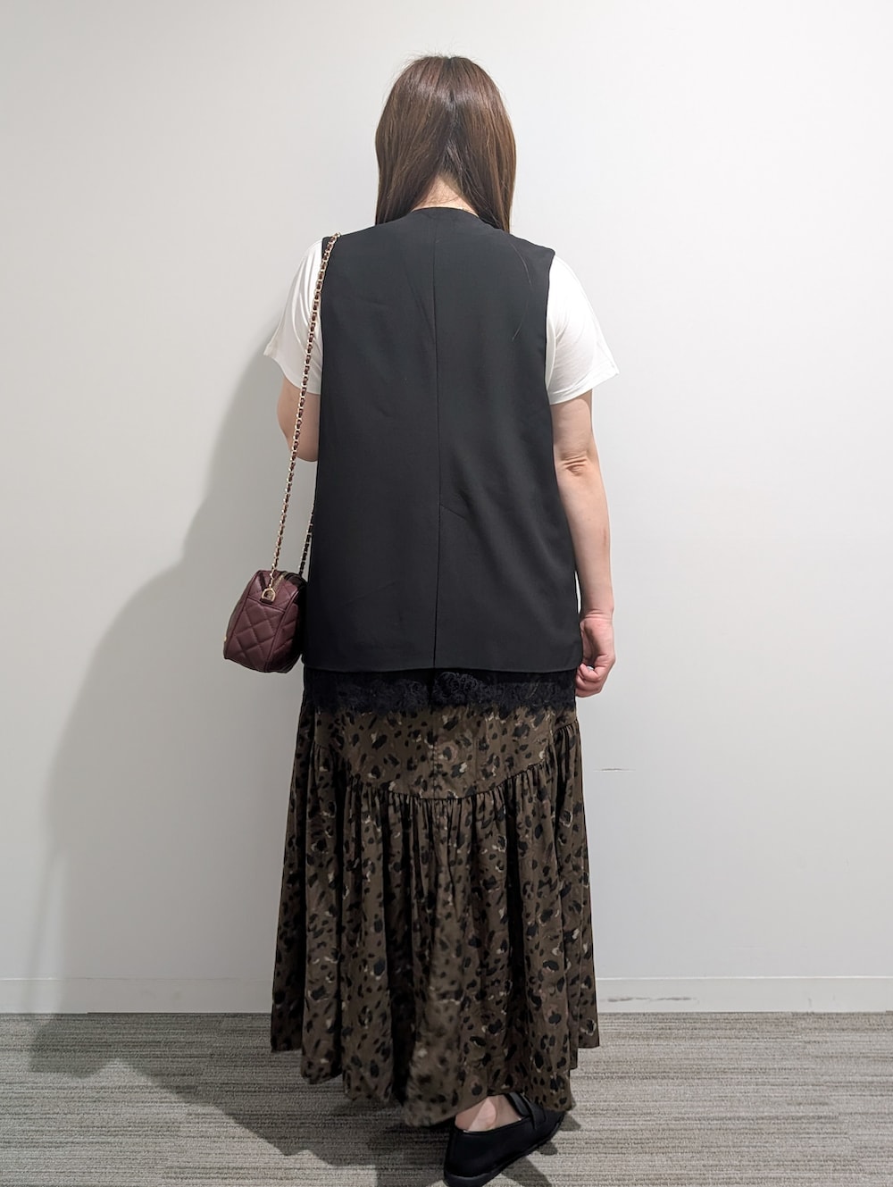 ブラック系のベスト、ホワイト系のTシャツ/カットソー、ブラウン系のスカートを着用したレディースの秋コーディネートの5枚目の写真