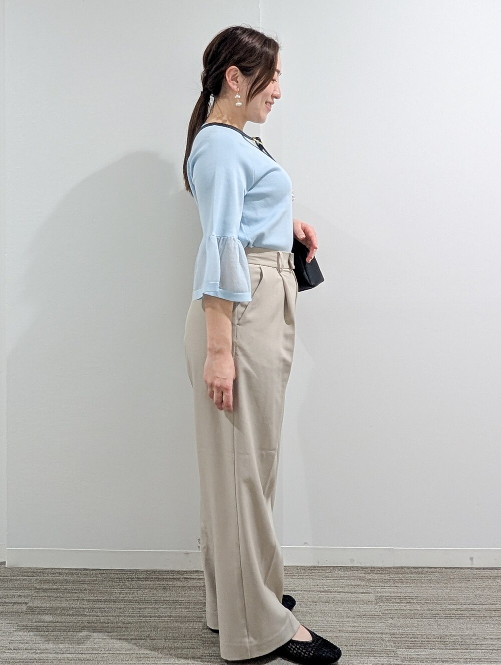 ブルー系のニット/セーター、ベージュ系のその他パンツ、ブラック系のショルダーバッグを着用したレディースの春コーディネートの7枚目の写真