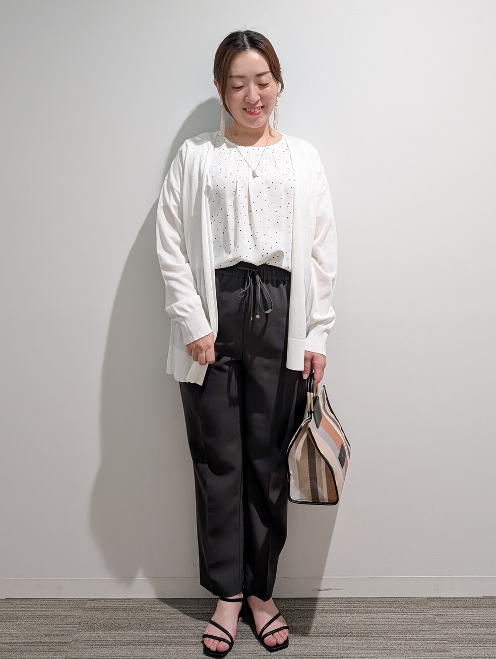 ホワイト系のシャツ/ブラウス、グレー系のその他パンツ、ブラック系のサンダルを着用したレディースの春コーディネートの2枚目の写真