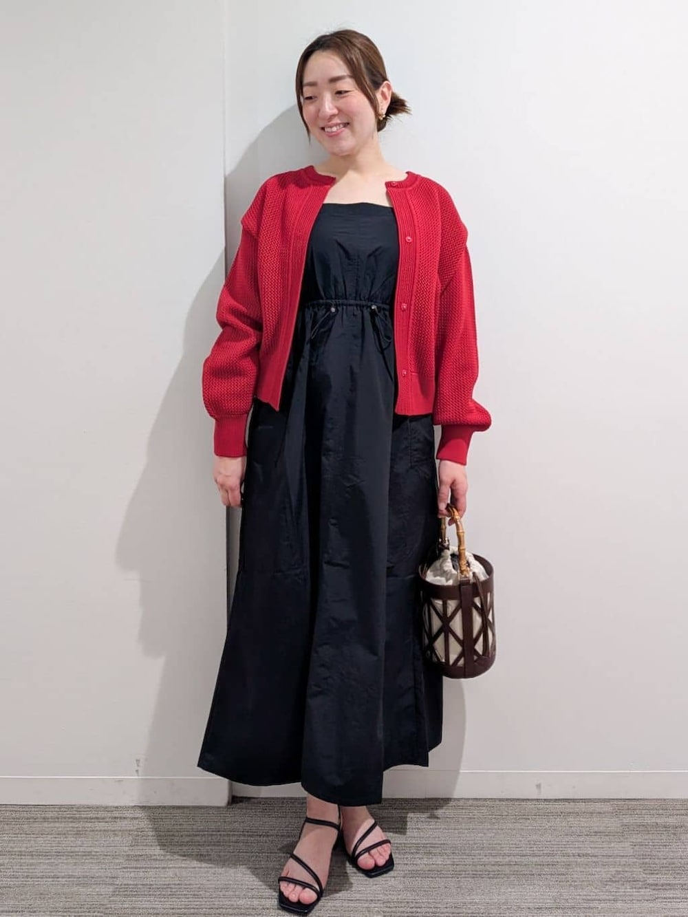 ブラック系のワンピース、レッド系のカーディガン/ボレロ、ブラック系のサンダルを着用したレディースの春コーディネートの3枚目の写真
