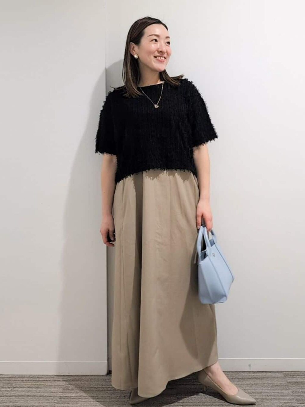 ブラック系のニット/セーター、ベージュ系のワンピース、ブルー系のトートバッグを着用したレディースの夏コーディネートの3枚目の写真