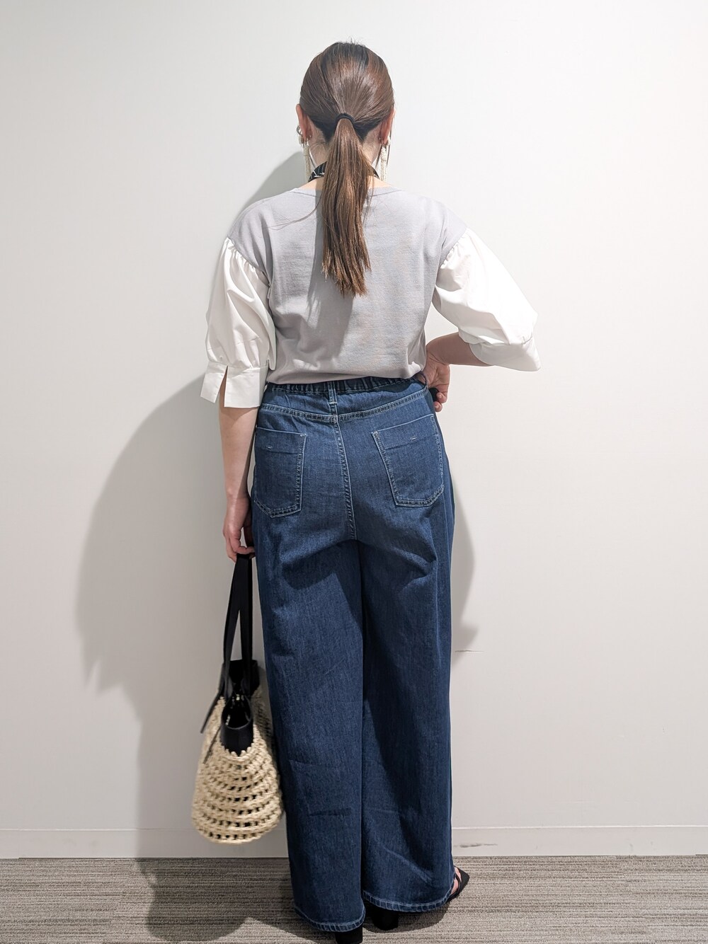 グレー系のニット/セーター、ブルー系のデニムパンツ、ブラック系のトートバッグを着用したレディースの夏コーディネートの4枚目の写真