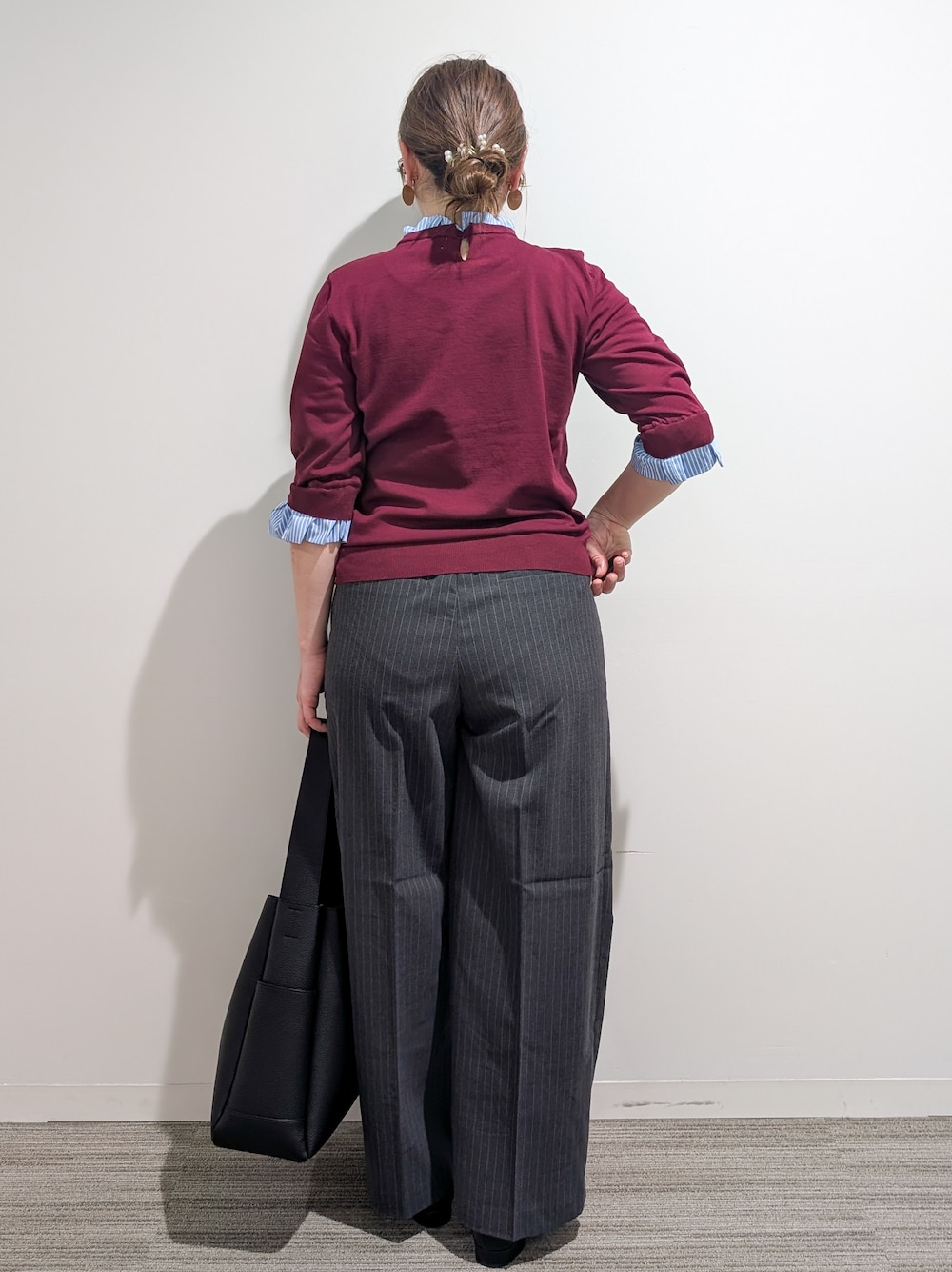 レッド系のニット/セーター、グレー系のその他パンツ、ブラック系のトートバッグを着用したレディースの秋コーディネートの4枚目の写真
