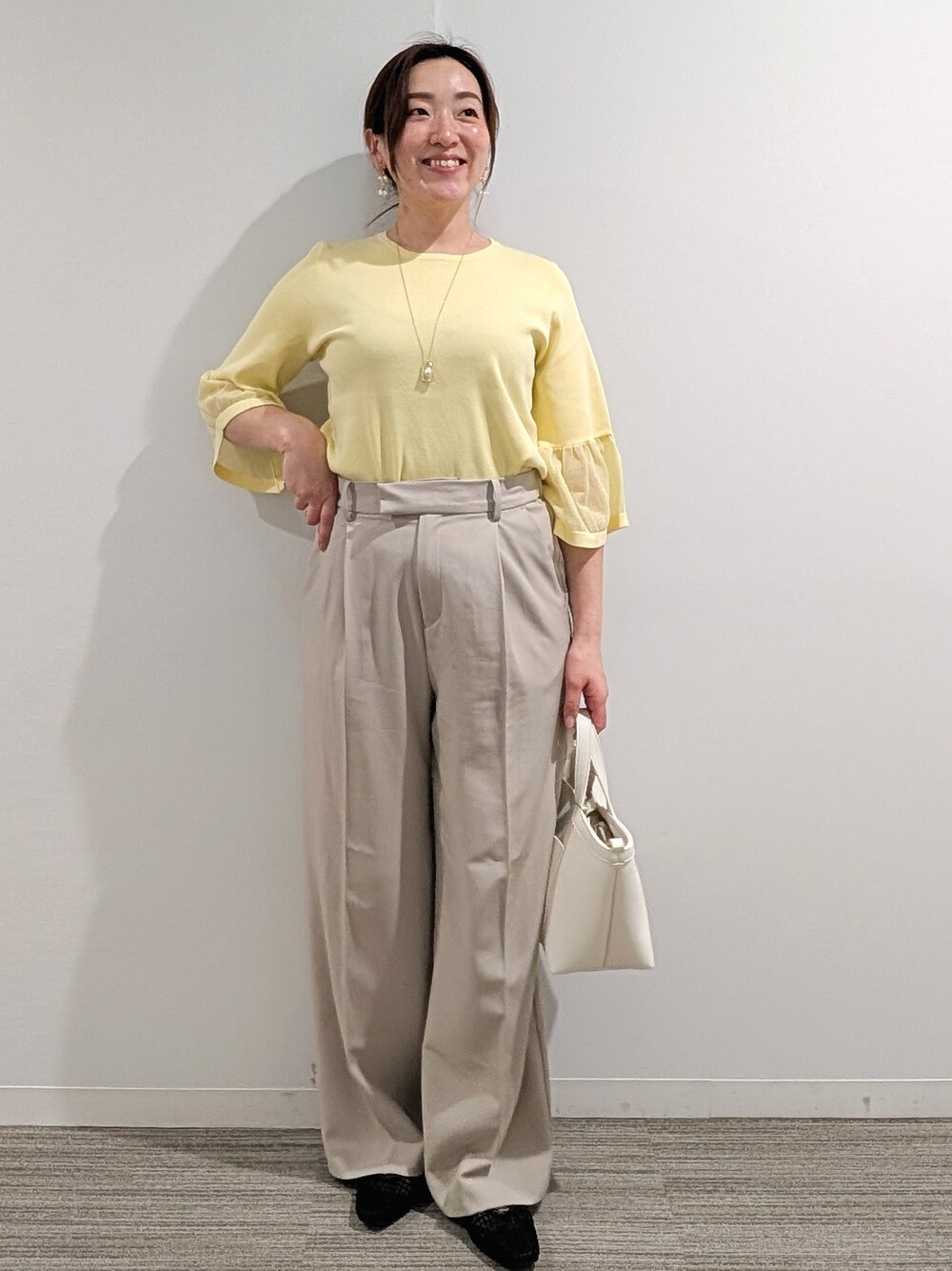 ブルー系のニット/セーター、ベージュ系のその他パンツ、ブラック系のショルダーバッグを着用したレディースの春コーディネートの9枚目の写真