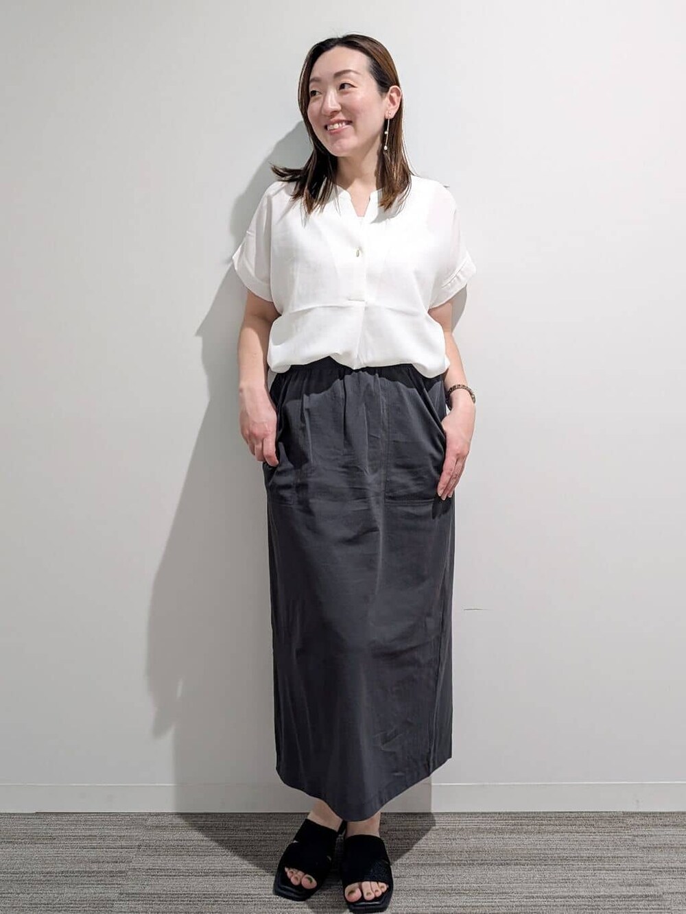 ホワイト系のシャツ/ブラウス、グレー系のスカート、ブラック系のサンダルを着用したレディースの夏コーディネートの2枚目の写真
