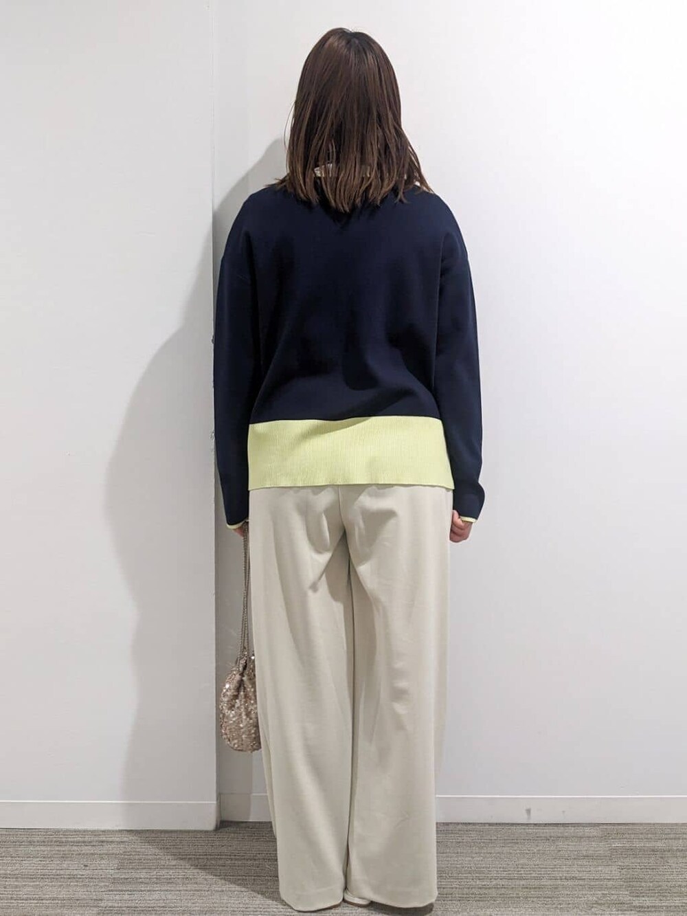 グレー系のノーカラーコート、ブルー系のニット/セーター、ホワイト系のTシャツ/カットソーを着用したレディースの春コーディネートの3枚目の写真