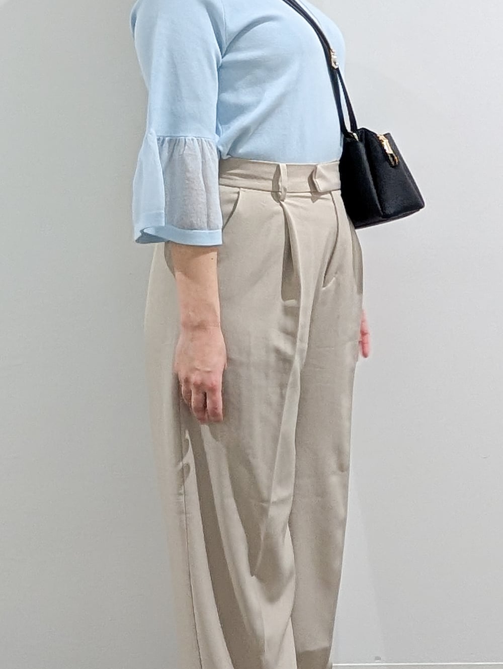 ブルー系のニット/セーター、ベージュ系のその他パンツ、ブラック系のショルダーバッグを着用したレディースの春コーディネートの3枚目の写真