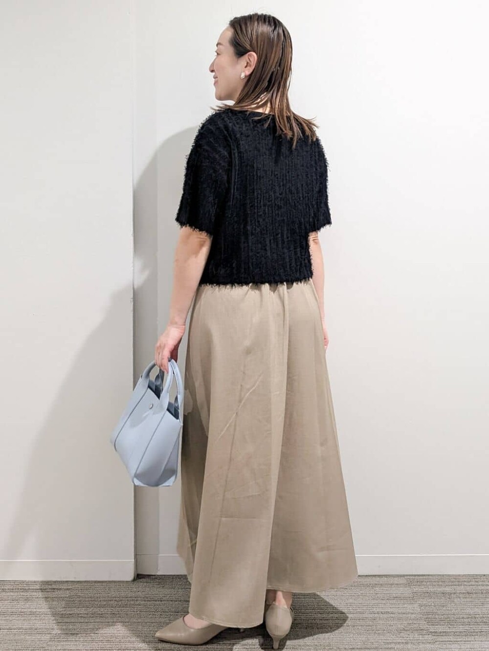 ブラック系のニット/セーター、ベージュ系のワンピース、ブルー系のトートバッグを着用したレディースの夏コーディネートの4枚目の写真