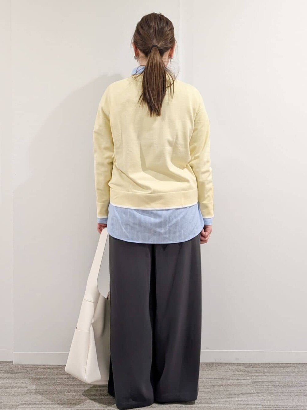 イエロー系のニット/セーター、ブルー系のシャツ/ブラウス、グレー系のその他パンツを着用したレディースの冬コーディネートの6枚目の写真