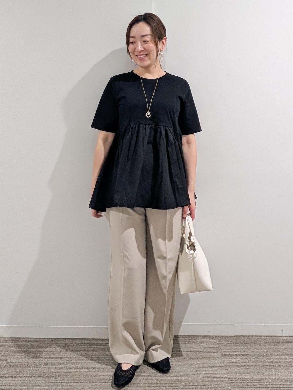 ブラック系のTシャツ/カットソー、ベージュ系のその他パンツ、ホワイト系のショルダーバッグを着用したレディースの春コーディネートの4枚目の写真