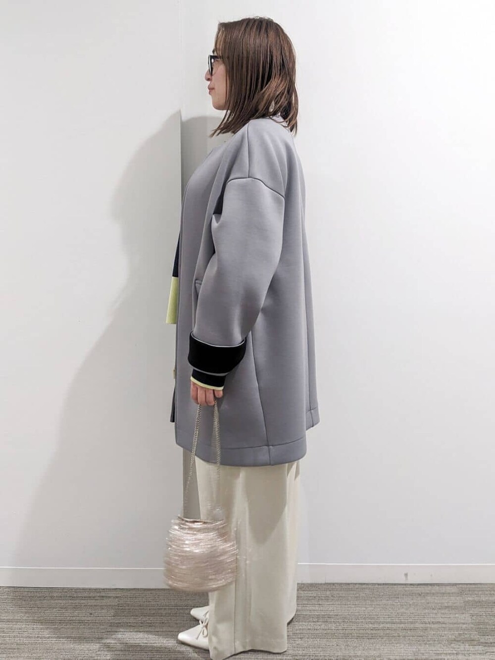 グレー系のノーカラーコート、ブルー系のニット/セーター、ホワイト系のTシャツ/カットソーを着用したレディースの春コーディネートの8枚目の写真