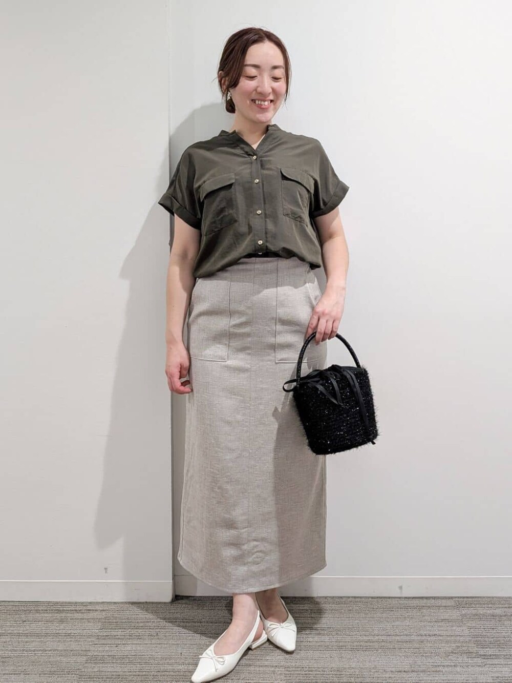 グリーン系のシャツ/ブラウス、ベージュ系のスカート、ブラック系のハンドバッグを着用したレディースの夏コーディネートの2枚目の写真