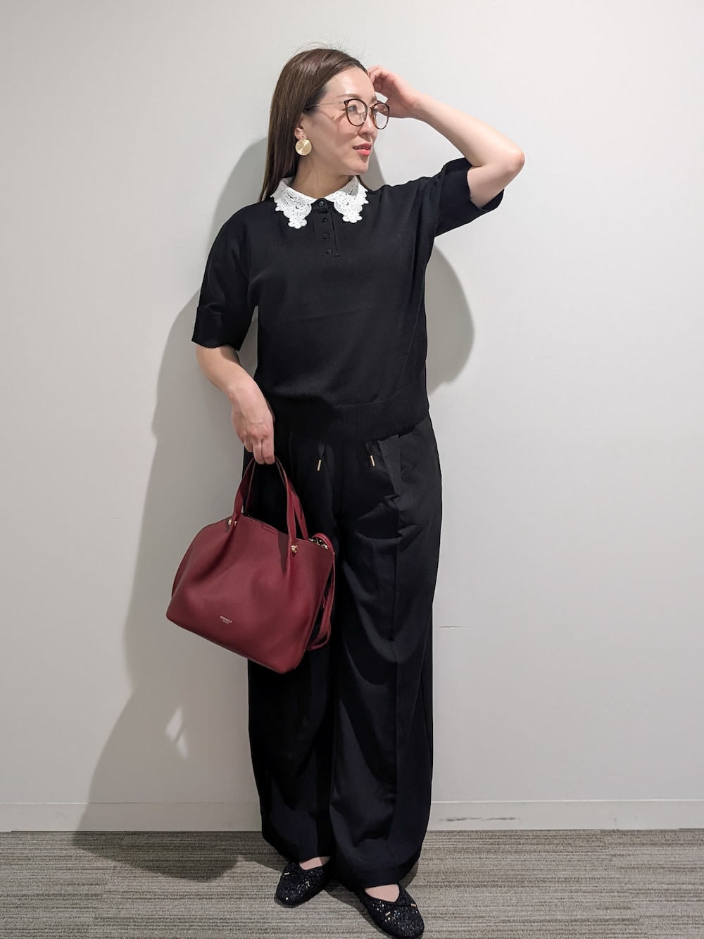 ブラック系のニット/セーター、ブラック系のその他パンツ、レッド系のショルダーバッグを着用したレディースの秋コーディネートの7枚目の写真
