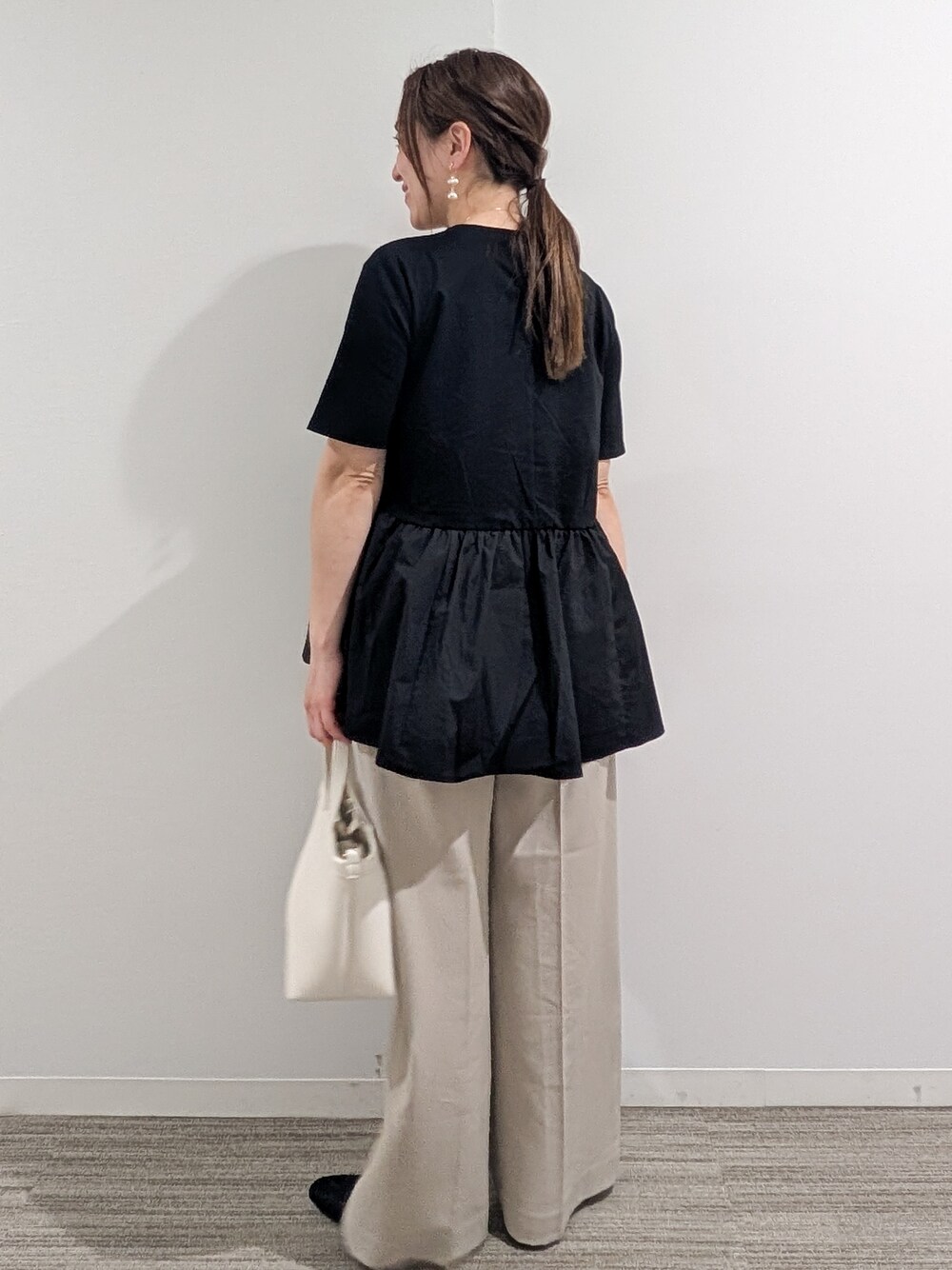 ブラック系のTシャツ/カットソー、ベージュ系のその他パンツ、ホワイト系のショルダーバッグを着用したレディースの春コーディネートの5枚目の写真
