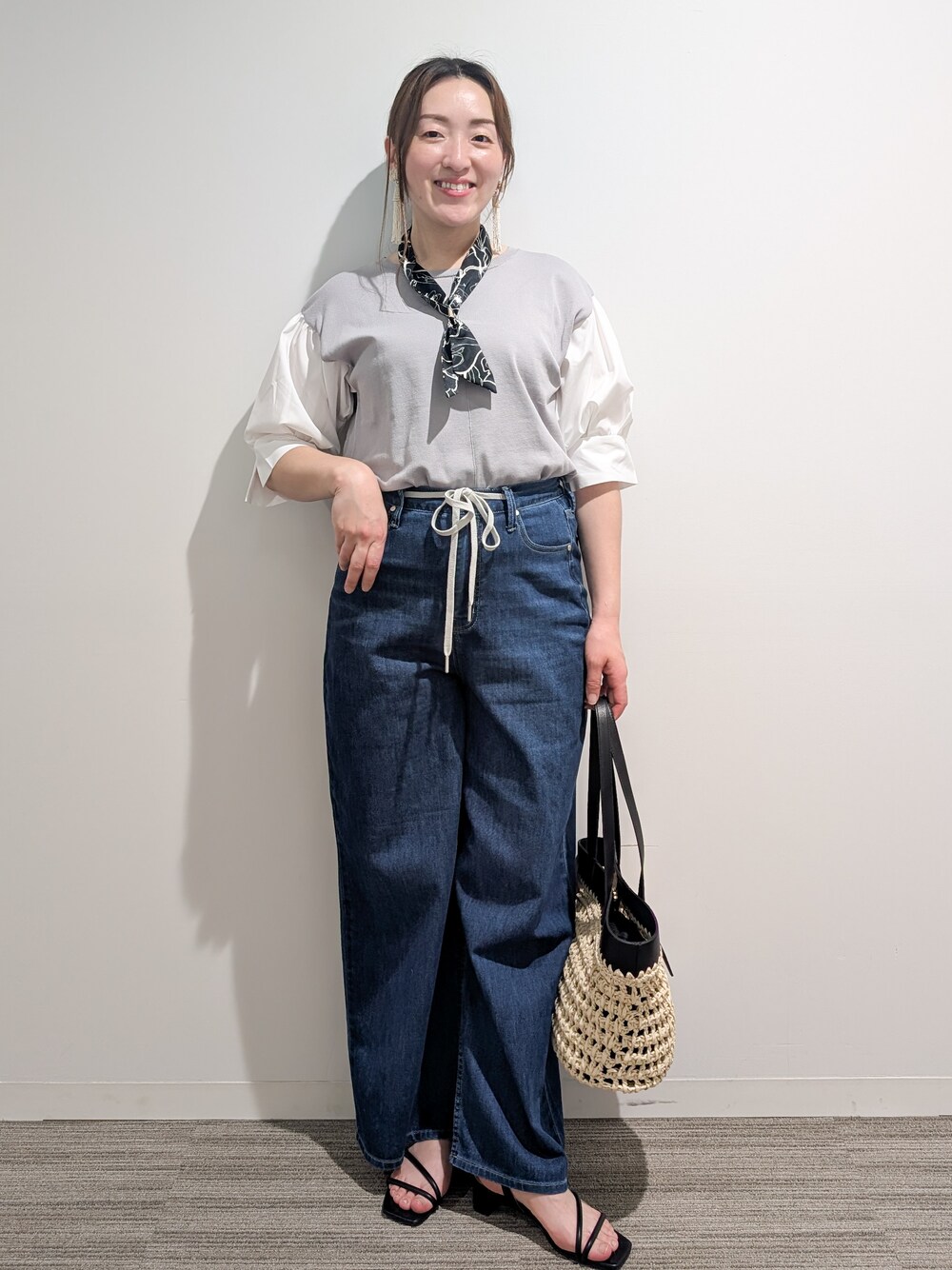 グレー系のニット/セーター、ブルー系のデニムパンツ、ブラック系のトートバッグを着用したレディースの夏コーディネートの2枚目の写真