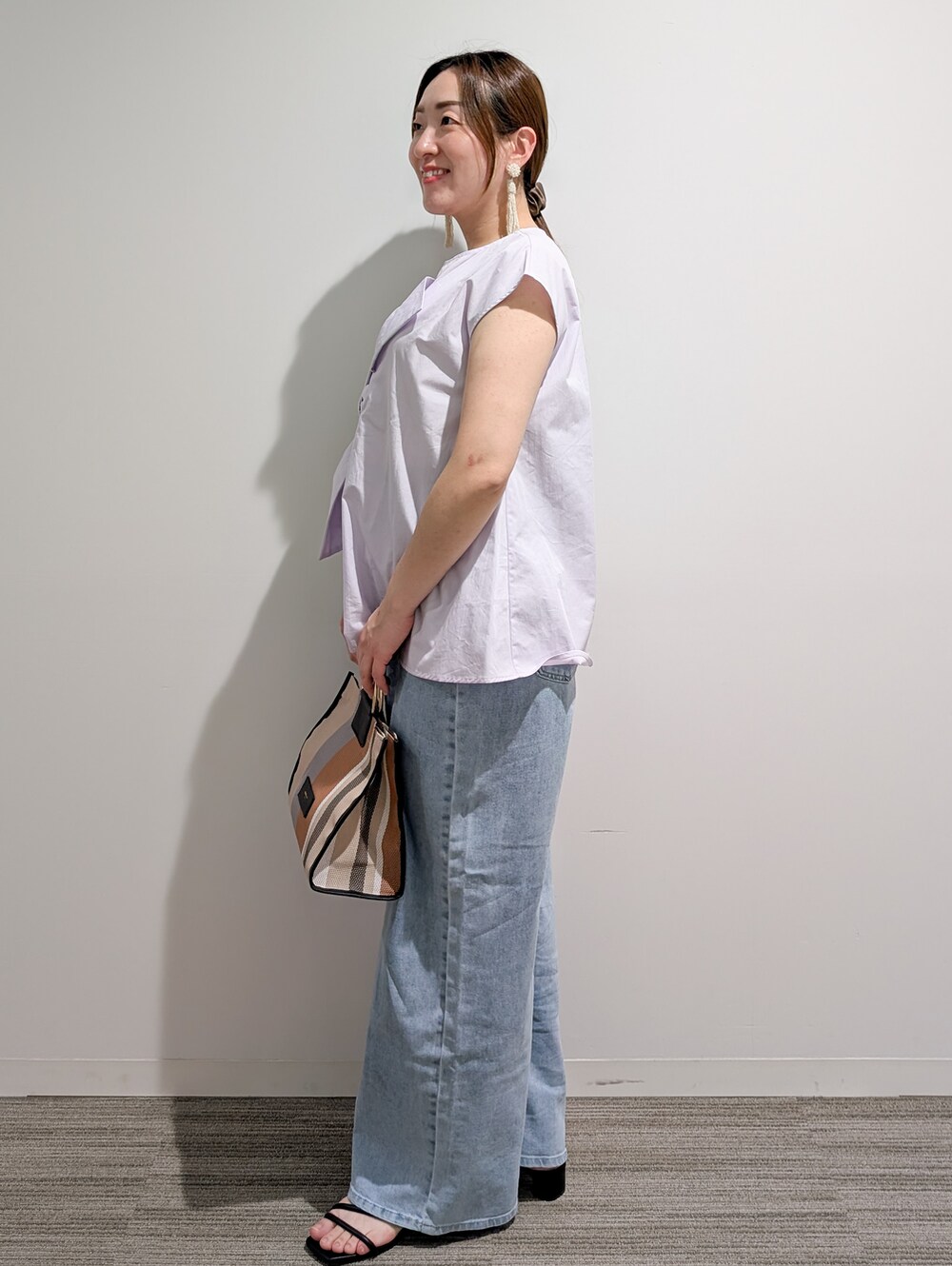 パープル系のシャツ/ブラウス、ブルー系のデニムパンツ、ブラック系のトートバッグを着用したレディースの夏コーディネートの2枚目の写真