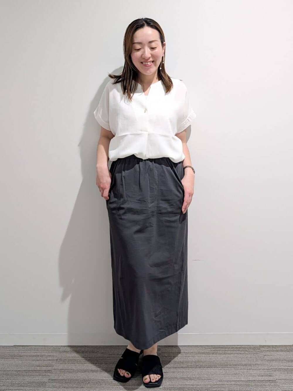 ホワイト系のシャツ/ブラウス、グレー系のスカート、ブラック系のサンダルを着用したレディースの夏コーディネートの10枚目の写真