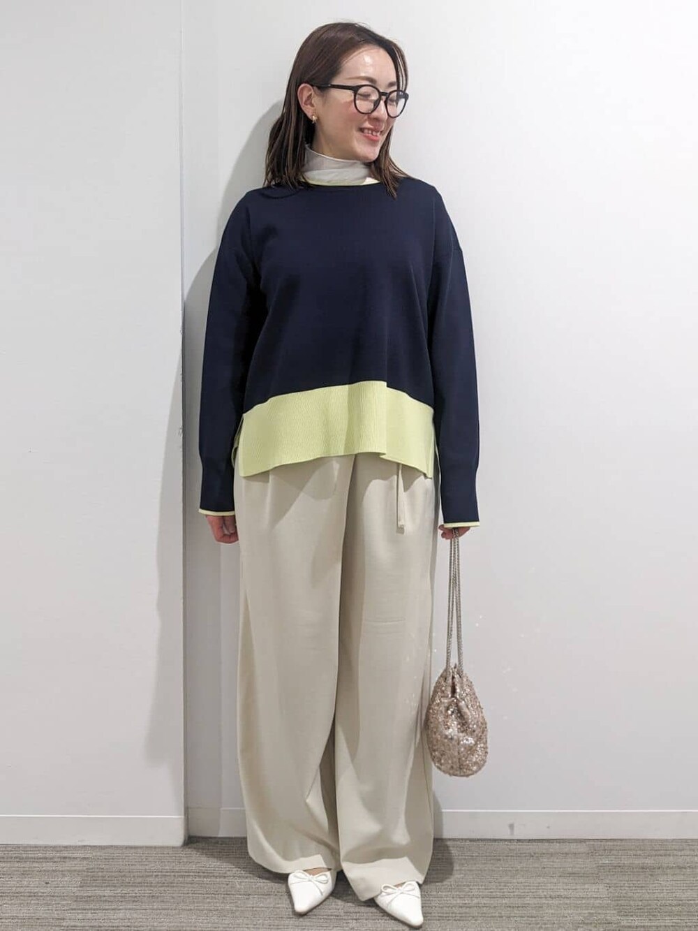 グレー系のノーカラーコート、ブルー系のニット/セーター、ホワイト系のTシャツ/カットソーを着用したレディースの春コーディネートの2枚目の写真
